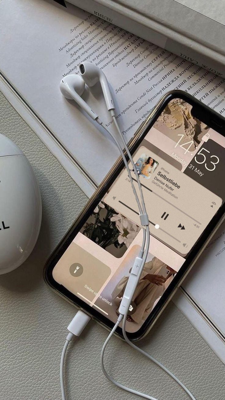 Handy mit Kopfhörern, auf dem Bildschirm läuft die Meditation Selbstliebe