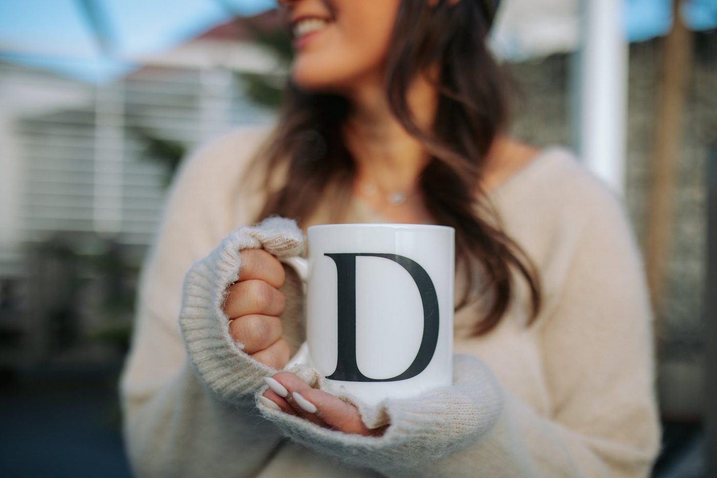 Hände mit einer Tasse mit dem Buchstaben D